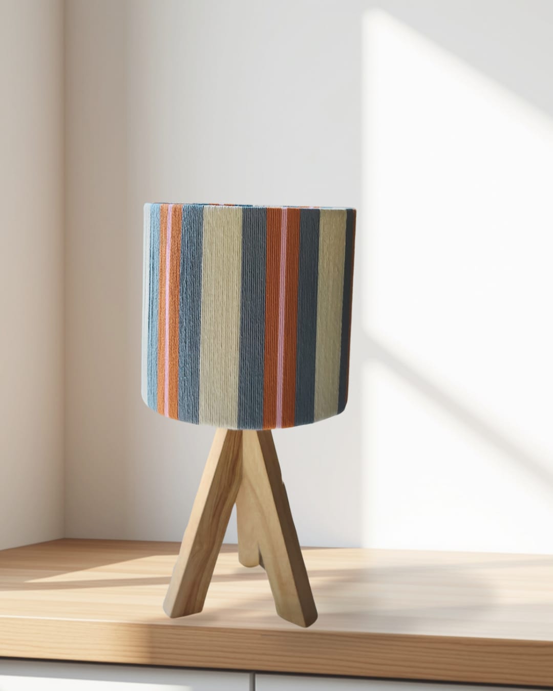 A blue and rust striped lamp on a counter in morning sun