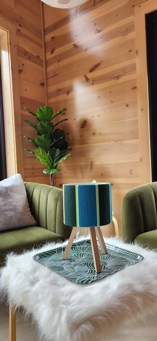 A teal and lime wrapped lamp on a sheepskin-covered table in a cabin