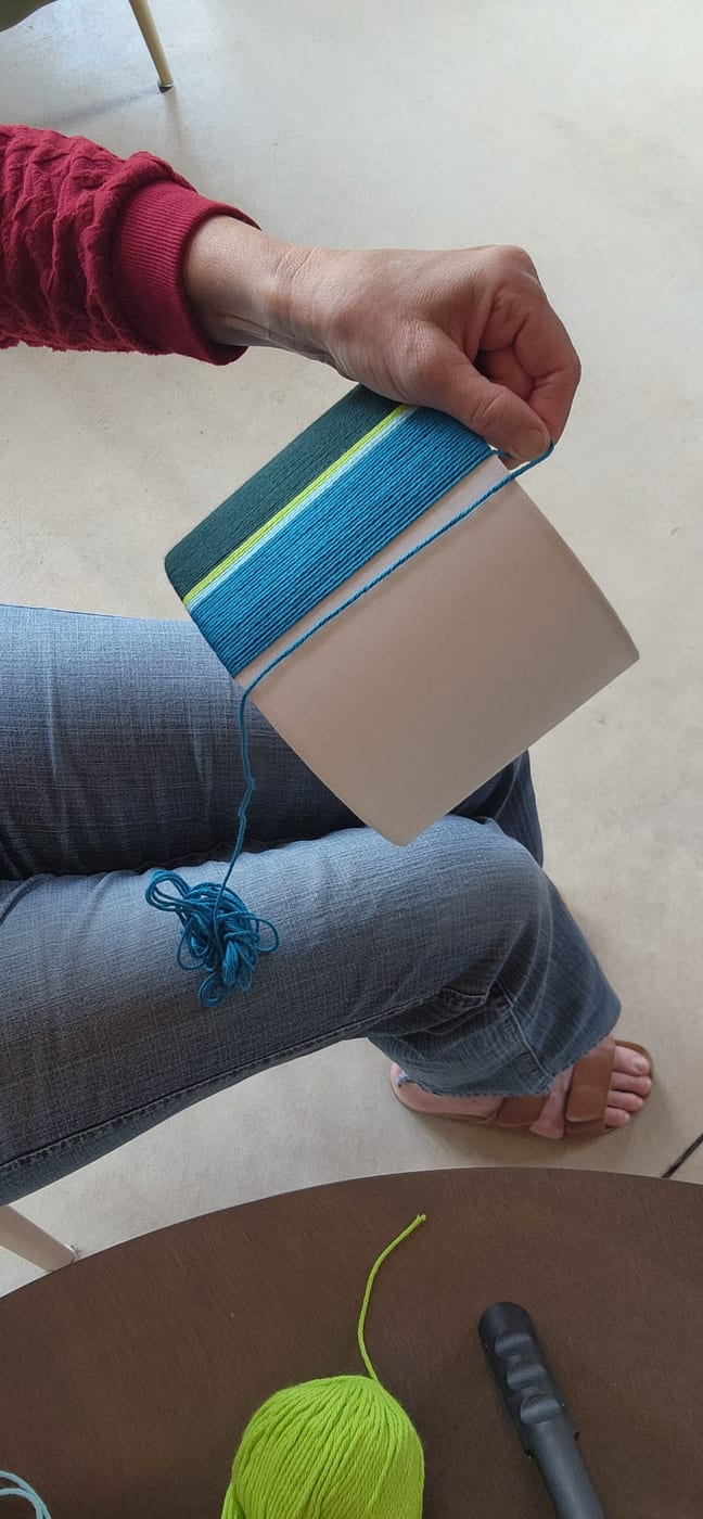 Lifting a blue and lime wrapped shade off a work surface